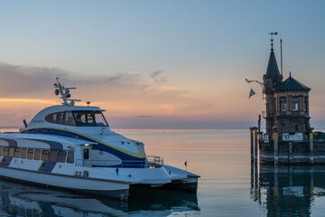 Beautiful sunrise view from Imperia statue to lighthouse at harbor entrance, catamaran ferry and...