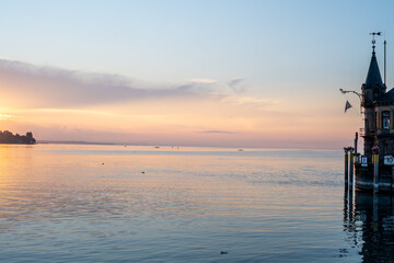 Beautiful sunrise view from Imperia statue to lighthouse at harbor entrance and Lake Constance in...