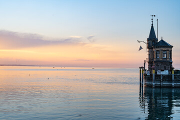 Beautiful sunrise view from Imperia statue to lighthouse at harbor entrance and Lake Constance in...