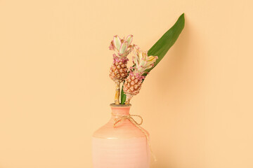 Vase with decorative pineapples and palm leaf on beige background