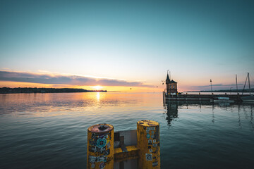 Panoramic sunrise view from Imperia statue to lighthouse at harbor entrance and Lake Constance in...