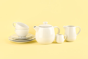 Stylish tea set on yellow background