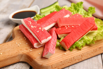 Board with tasty crab sticks on light wooden background © Pixel-Shot