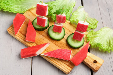 Board with tasty crab sticks on light wooden background © Pixel-Shot