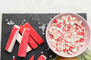 Slate board with tasty crab sticks on light wooden background, closeup © Pixel-Shot