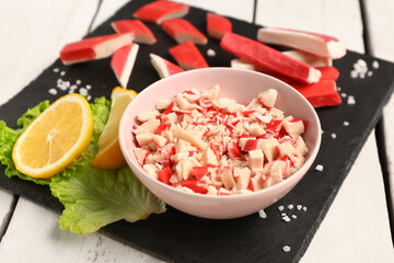Bowl with tasty chopped crab sticks on light wooden background © Pixel-Shot