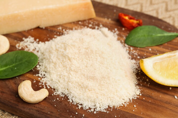 Wooden board with tasty grated Parmesan cheese on table, closeup