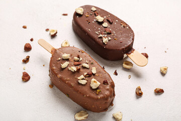 Delicious chocolate covered ice cream with crushed nuts on white table