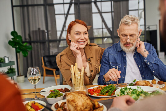 Pleased Parents Having Family Dinner Near Gay Couple On Blurred Foreground. 