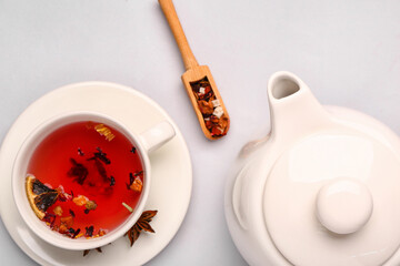 Ceramic teapot with cup of fruit tea on grey background