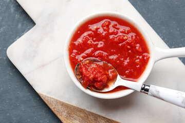 Bowl with tasty tomato sauce on table, closeup