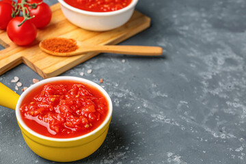 Bowl with tasty tomato sauce on blue background