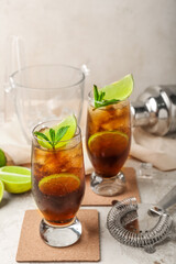 Glasses of cold Cuba Libre cocktail on light background