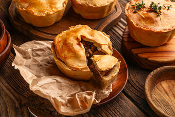 Plate with tasty meat pot pies on wooden background © Pixel-Shot
