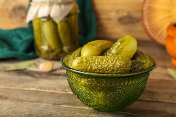 Bowl with tasty canned cucumbers on wooden table