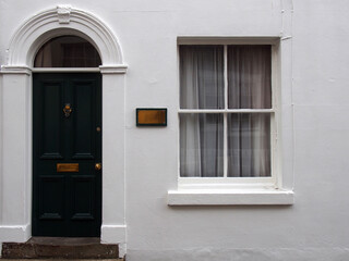 front view of a typical old small white painted english terraced house with black door