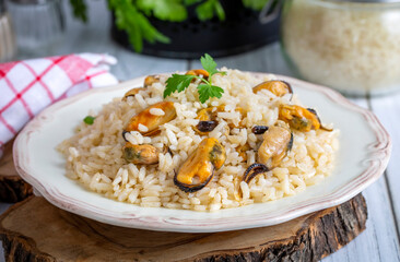 Mussel rice pilaf. Rice with mussels on small white plate on ceramic.