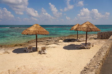Beach umbrellas made of straw on the shores of the Caribbean Sea in Mexico.