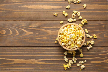 Bowl with crispy popcorn on wooden background
