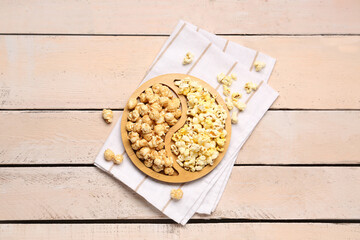 Plate with crispy popcorn on white wooden background