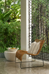 Half opened lounge area with all natural materials made furniture, rattan chairs with greenery behind