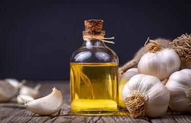 Obraz na płótnie Canvas Fresh garlic and garlic oil on the wooden background
