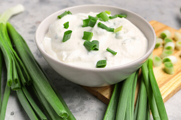 Bowl of tasty sour cream with green onion on table