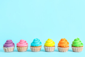Tasty colorful cupcakes on blue background