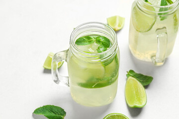 Mason jars of tasty mojito on light background