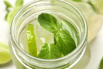 Mason jar of tasty mojito on table, closeup