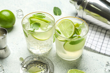 Glasses of tasty mojito on light background