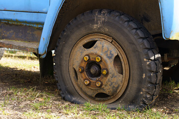 Fototapeta na wymiar A flat tire of an old fragment of a rusty abandoned broken truck.