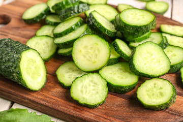 Wooden board with pieces of fresh cucumber on table, closeup
