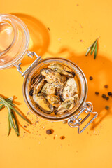 Jar with pickled mussels on orange background