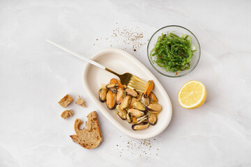 Plate with pickled mussels and bowl of seaweed salad on white background © Pixel-Shot