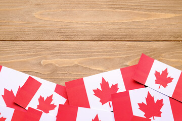 Paper flags of Canada on wooden background