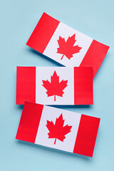 Paper flags of Canada on blue background