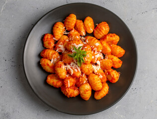 Traditional Italian food potato gnocchi with tomato sauce, parmesan cheese and fresh basil on dark table. Top view. Healthy food.