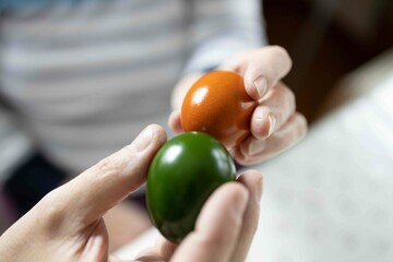 Close up of a hands of senior couple holding colored Easter eggs 