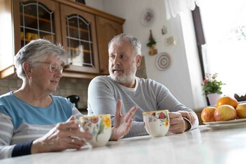 85 years old grey haired grandmother speak with the sun while drinking a tee in the kitchen 