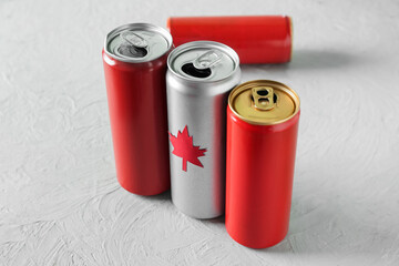 Cans of drink with maple leaf on grey table, closeup. Canadian flag concept