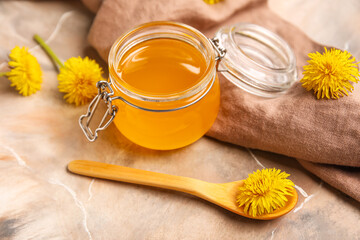 Jar with dandelion honey on marble background