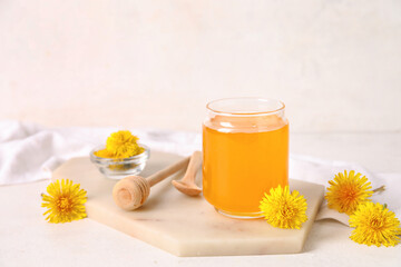 Obraz na płótnie Canvas Board with jar of dandelion honey on white table