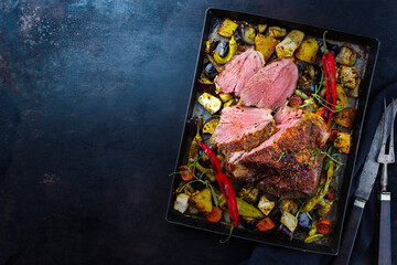 Traditional Greek barbecue leg of lamb with vegetable and feta cheese served as top view on a...