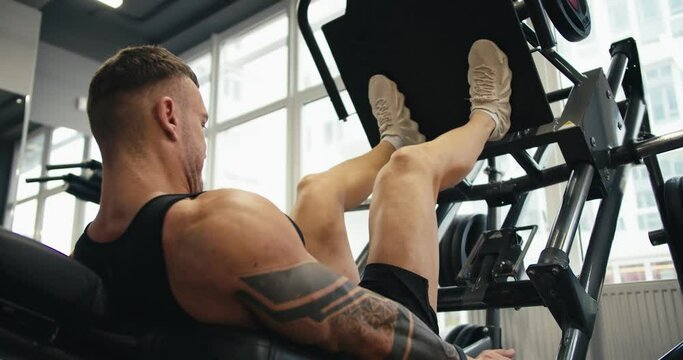 A muscular man performs exercises on a sports training apparatus for leg muscles in a gym, lifting weights Generative AI