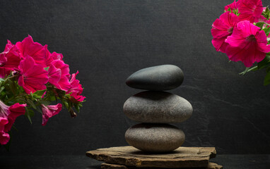 Fototapeta na wymiar background podium for product presentation with zen stones .gray oval stones on a gray background with flowers