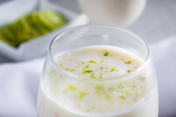 Delicious lemon mousse on a straw plate and a white table background, with whole and sliced lemons in the background, and a metal spoon