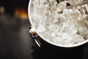 Ice cubes background. Metal bucket. Alcohol serving bar. Whisky on rocks drinking. Black bar counter. Exclusive cocktail bar background.