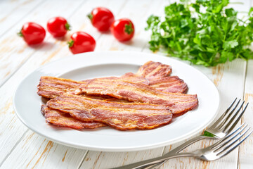 fried bacon strips with bbq sauce in a dish on a white table.