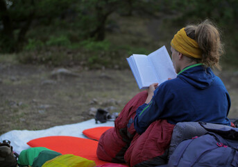 Female hiker reading book while camping